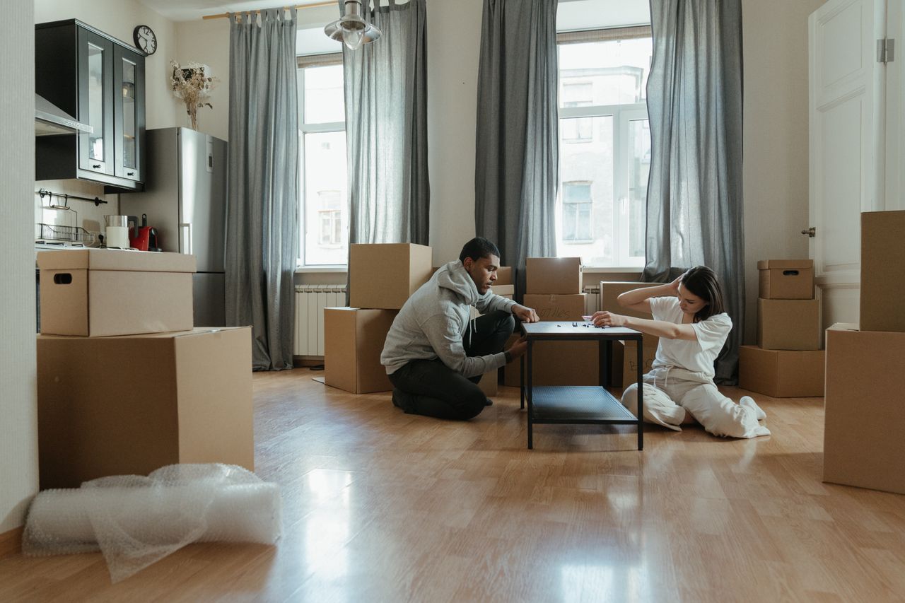 creative Young couple assembling furniture in their new apartment, surrounded by cardboard boxes.